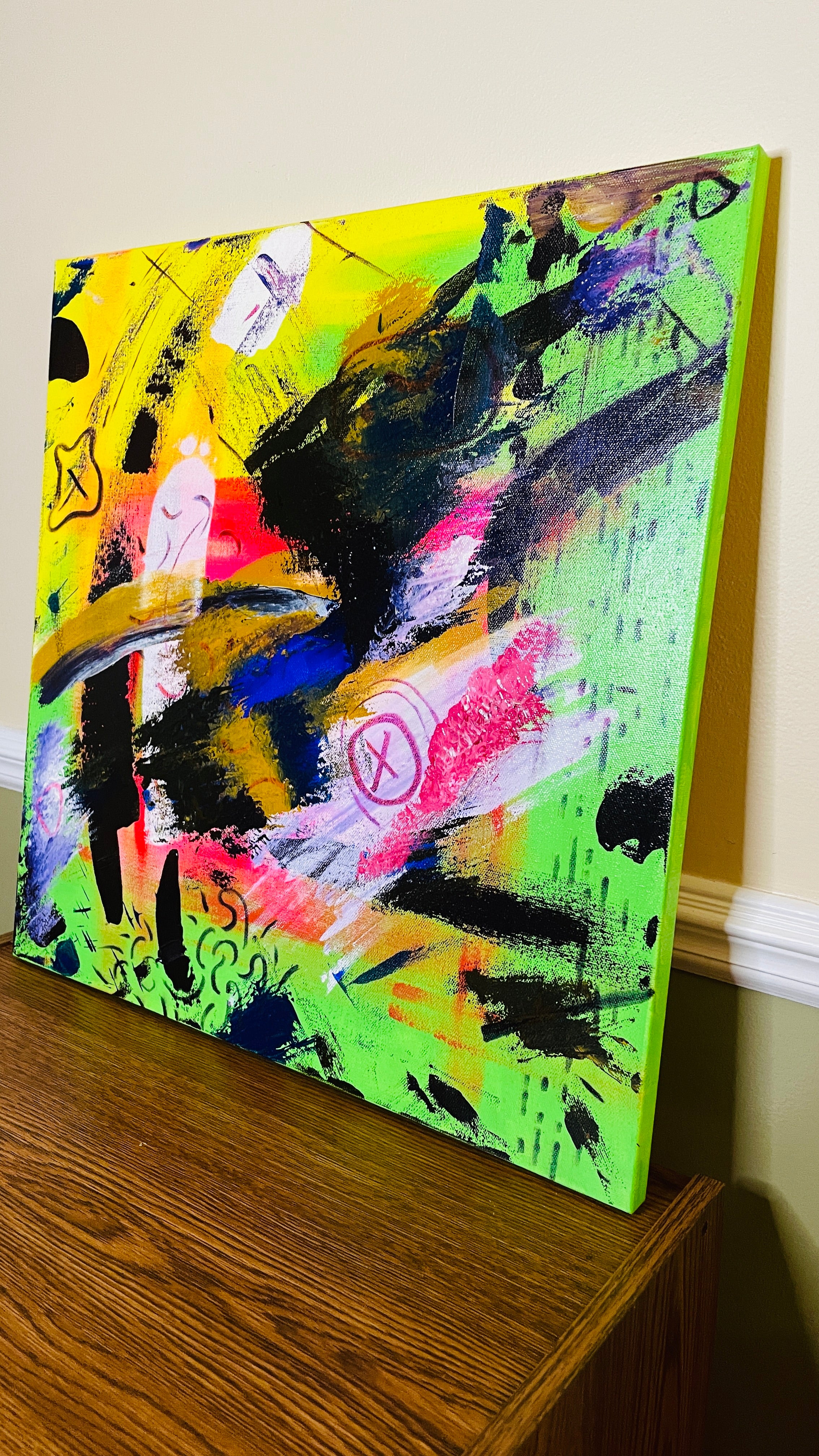 Square abstract mixed-media painting with neon yellow and green fields, sweeping black strokes, pink, blue, gold and white layers, pale simplified figures, crossed-out symbols, drawn lines and heavily textured passages.